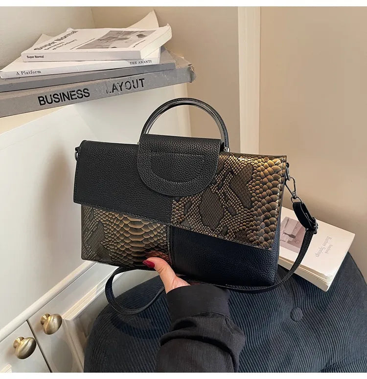 Structured handbag with contrasting reptile-texture panels — black and brown held in one hand | BTendance