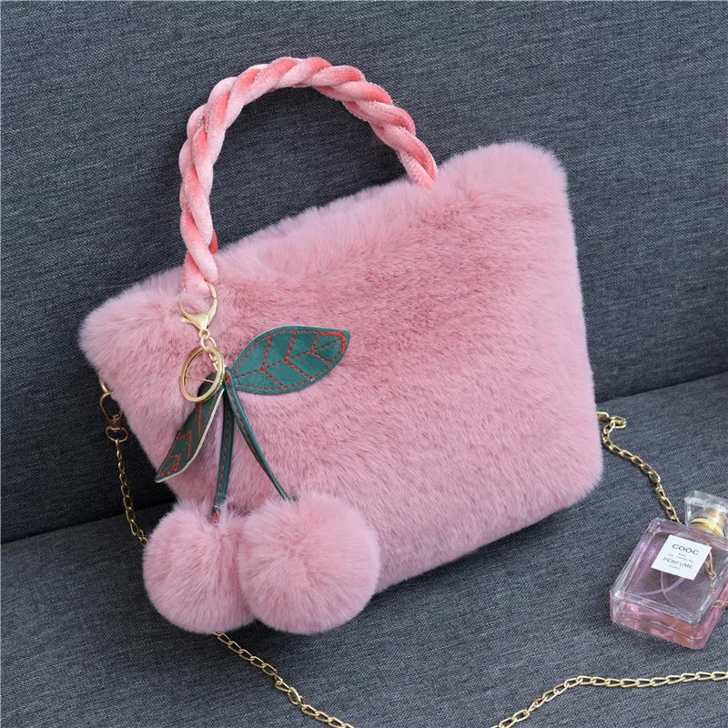 Plush handbag with twisted pink handles and pom-pom cherry charm — mauve on grey chair | BTendance