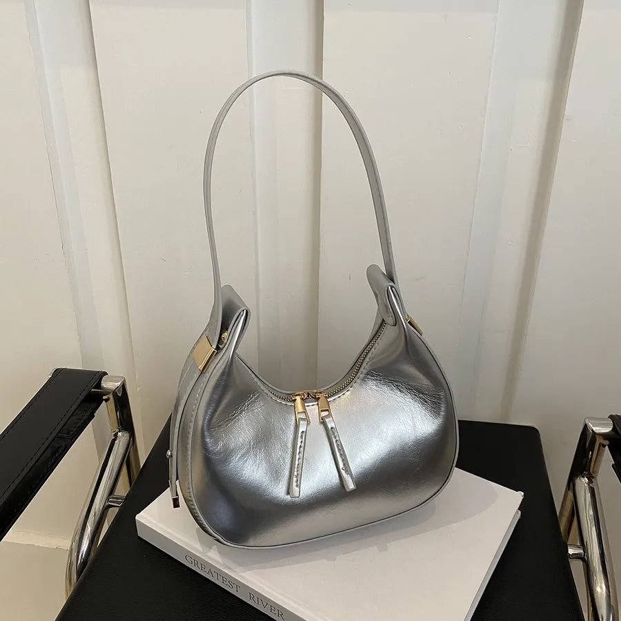 Curved zip shoulder bag – Silver bag displayed on a table | BTendance