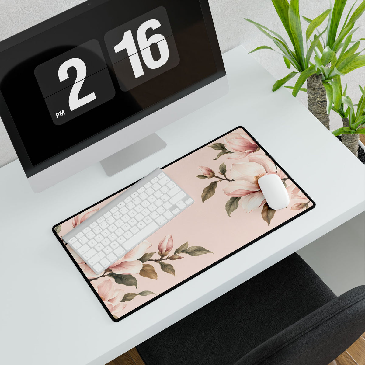 Blush Pink Magnolia Desk Mat, 23.6 × 13.8 in, angled computer desk mockup with plant.