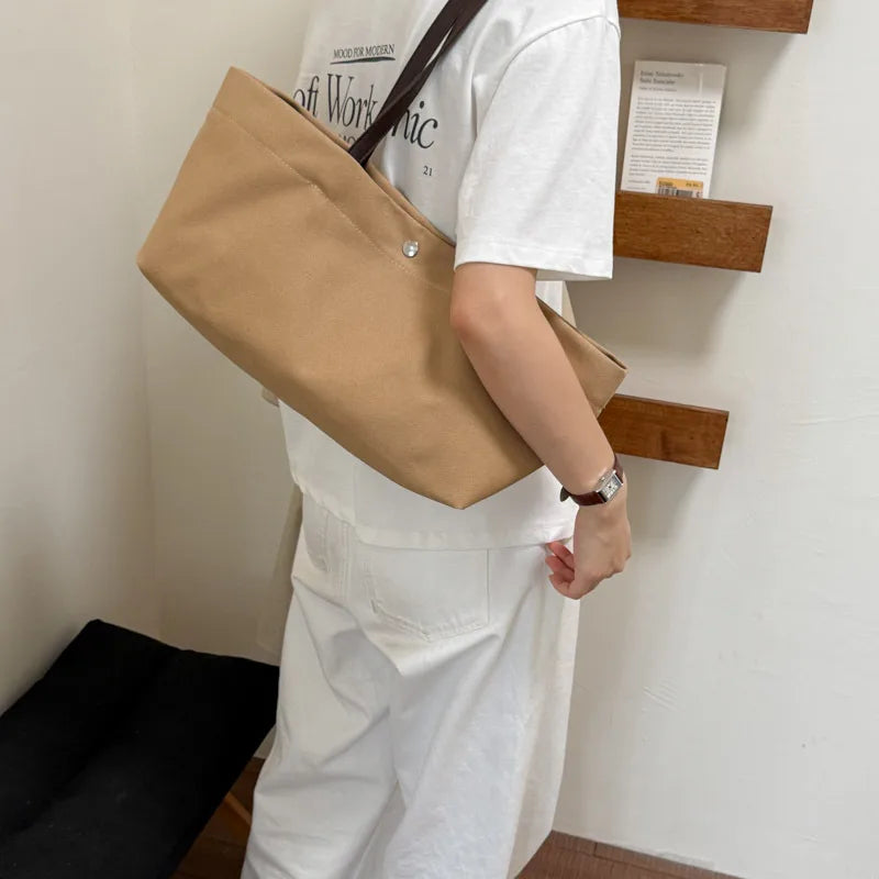 Wide canvas tote with contrasting dark shoulder handles — tan worn on shoulder | BTendance