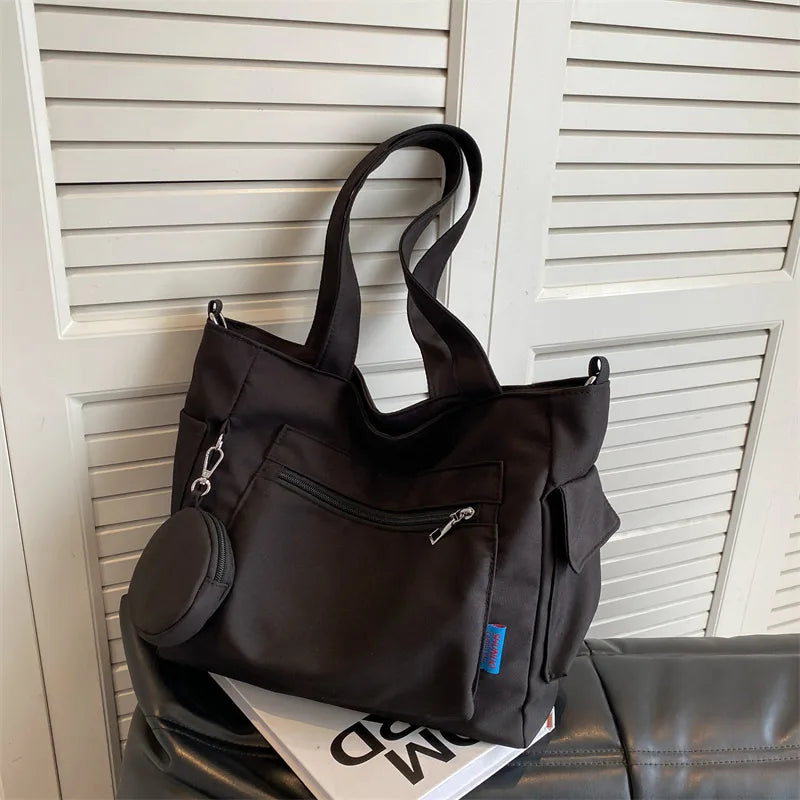 Pocket tote bag with round pouch – Black bag hanging against a wall | BTendance