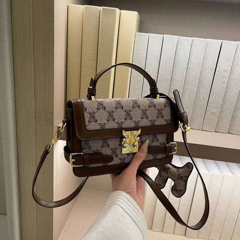 Bear pattern top handle bag with charm – Brown bag held in front of books | BTendance