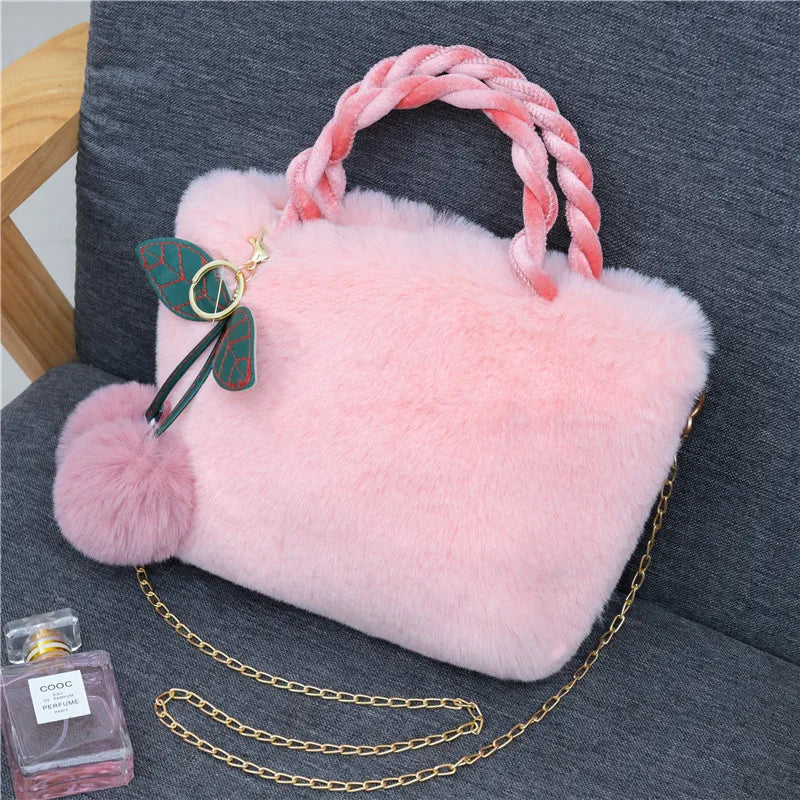 Plush handbag with twisted pink handles and pom-pom cherry charm — light pink on grey chair | BTendance