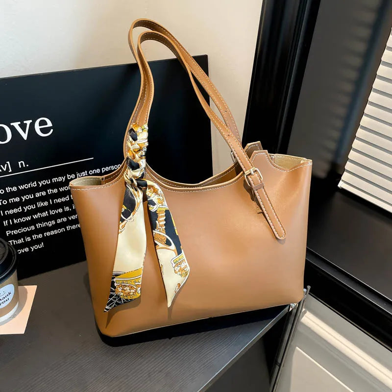 Shoulder tote bag with patterned scarf – Tan bag beside a window | BTendance