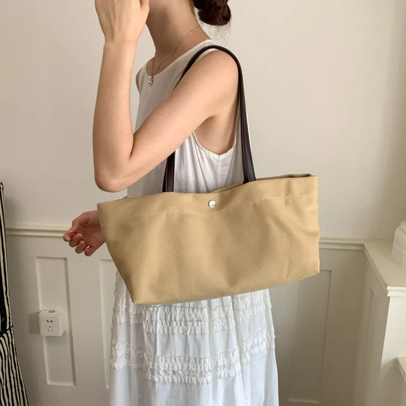 Wide canvas tote with contrasting dark shoulder handles — beige worn with white dress | BTendance