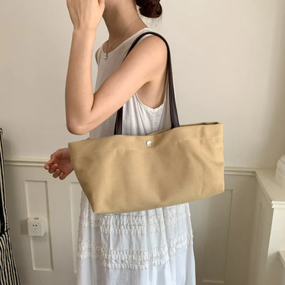 Wide canvas tote with contrasting dark shoulder handles — beige worn with white dress | BTendance