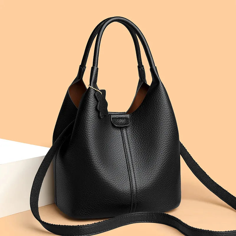 Bucket handbag with shoulder strap and bear charm – Black bag at an angle on peach background | BTendance