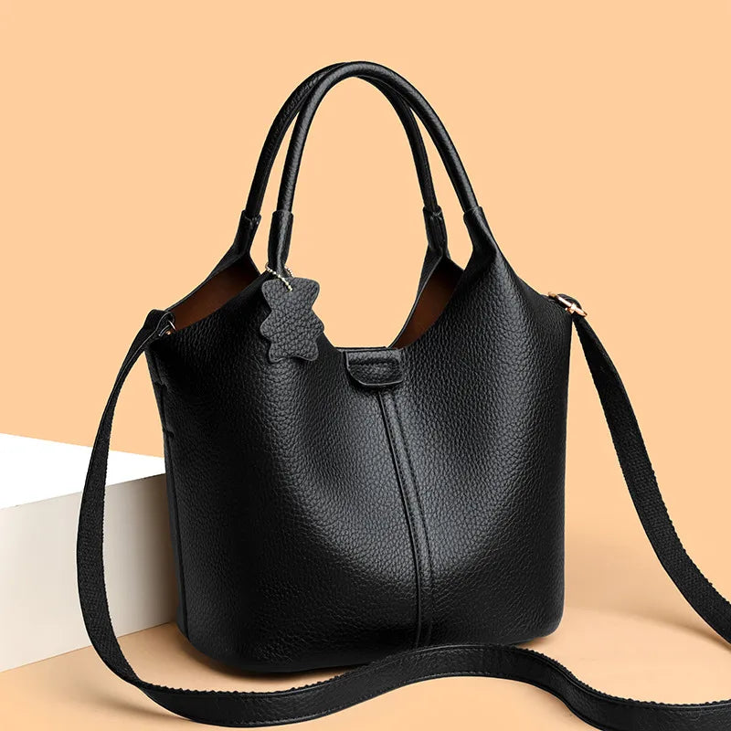 Bucket handbag with shoulder strap and bear charm – Black bag facing forward on peach background | BTendance