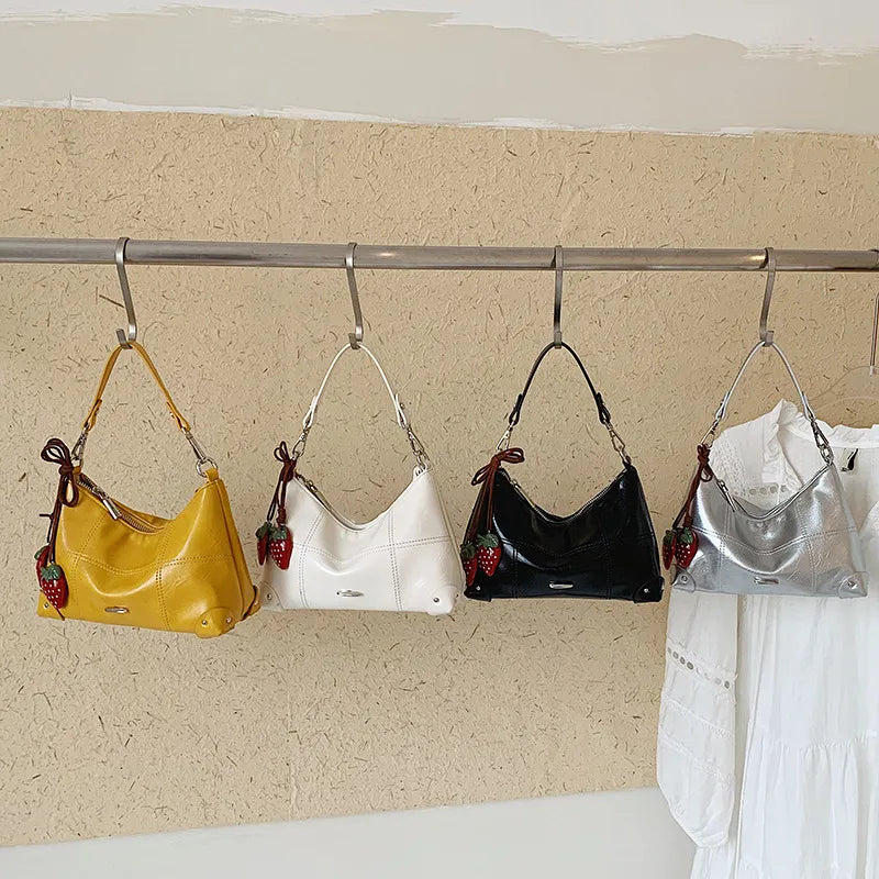 Glossy shoulder bag with strawberry charm – Four colours hanging on a rail | BTendance