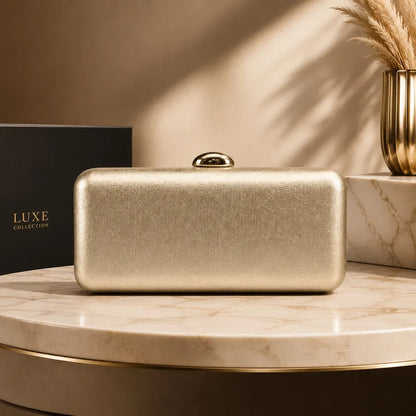 Rectangular evening clutch with oval metal clasp — gold on marble display | BTendance