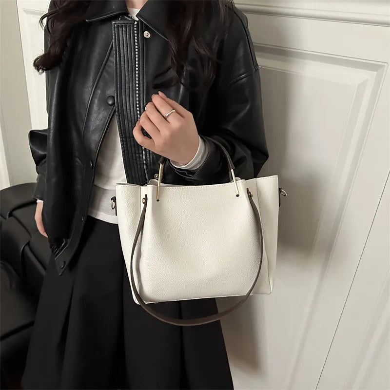 Textured bucket handbag with contrasting dark handles — white worn over black jacket | BTendance