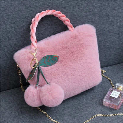 Plush handbag with twisted pink handles and pom-pom cherry charm — mauve on grey chair | BTendance