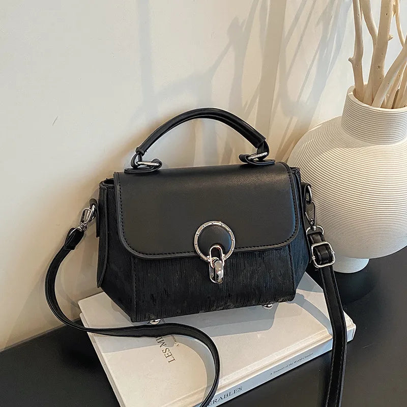 Ring clasp top handle crossbody bag – Black bag beside a vase | BTendance