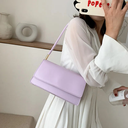 Slim rectangular flap shoulder bag with gold-tone strap accents — lilac worn on shoulder | BTendance