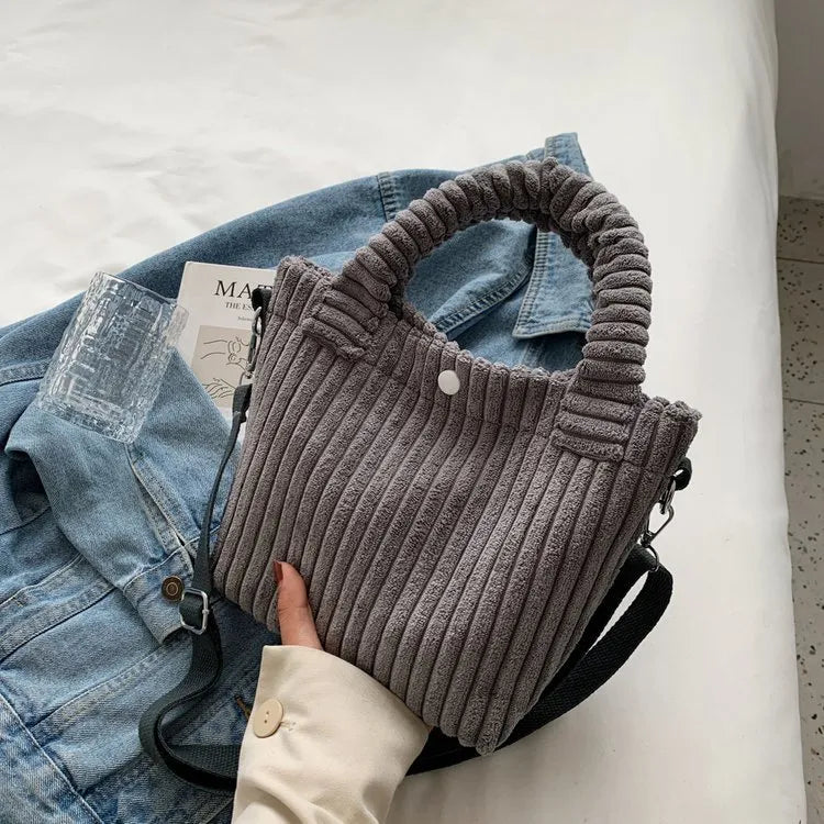 Ribbed plush handbag with rounded handles and long strap — grey on denim display | BTendance