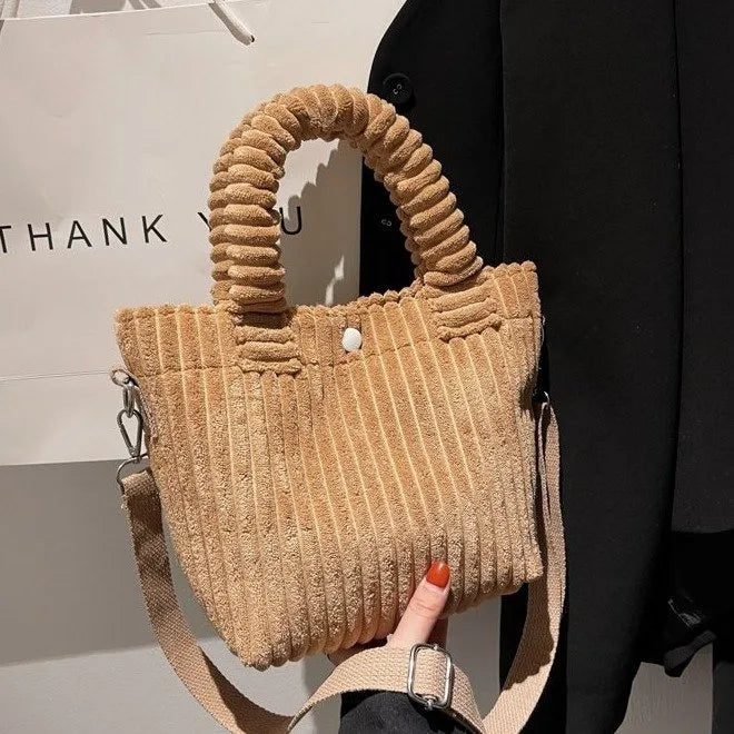 Ribbed plush handbag with rounded handles and long strap — tan held in one hand | BTendance