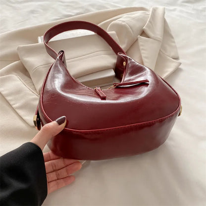 Curved zip shoulder bag – Burgundy bag held to show its base | BTendance