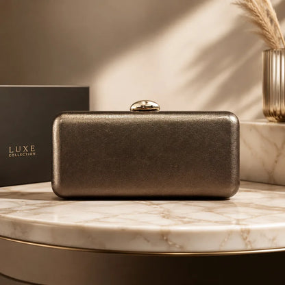 Rectangular evening clutch with oval metal clasp — bronze on marble display | BTendance