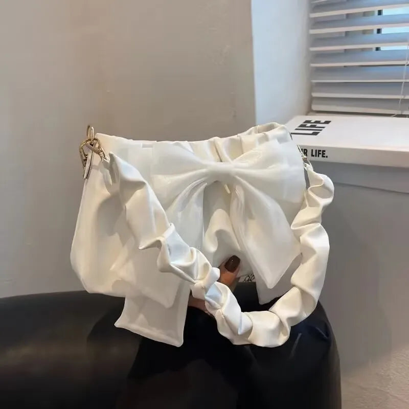 Bow-detail shoulder bag with gathered handle — white with matching bow held in one hand | BTendance