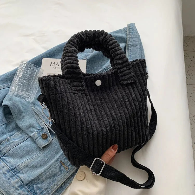 Ribbed plush handbag with rounded handles and long strap — black on denim display | BTendance