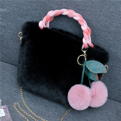 Plush handbag with twisted pink handles and pom-pom cherry charm — black on grey chair | BTendance