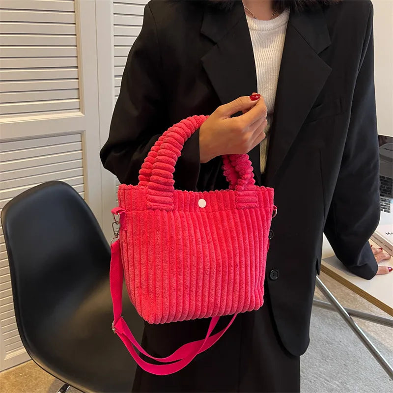 Ribbed plush handbag with rounded handles and long strap — bright pink held by model | BTendance