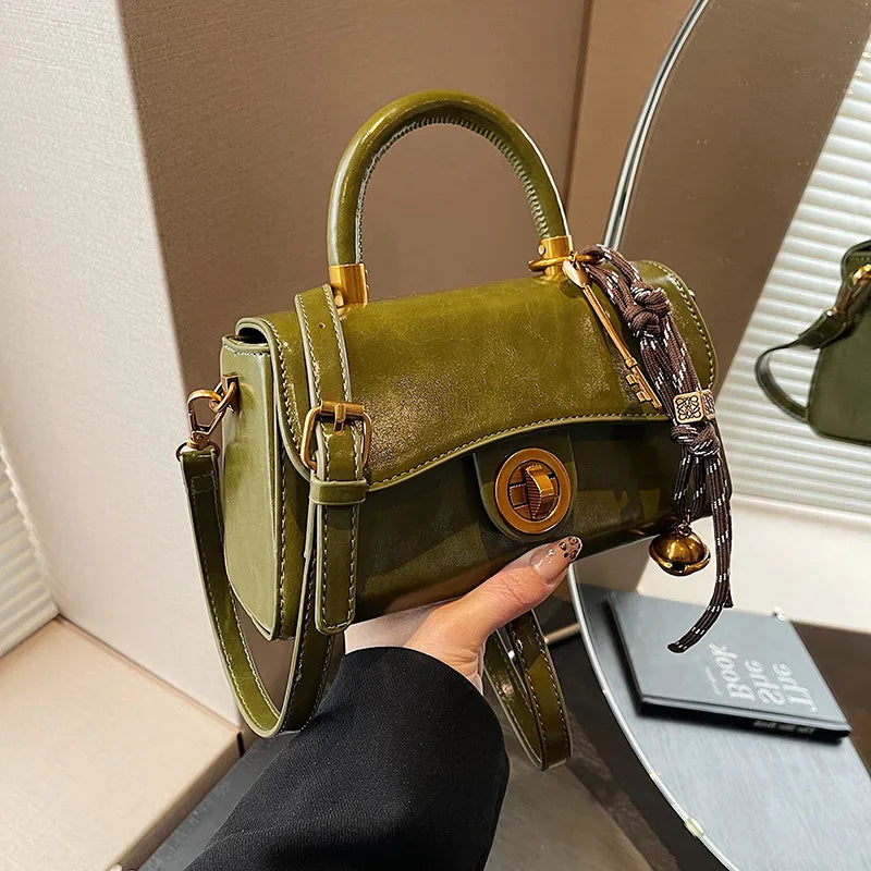 Structured top-handle flap handbag with round gold-tone clasp — green with scarf accent held in one hand | BTendance