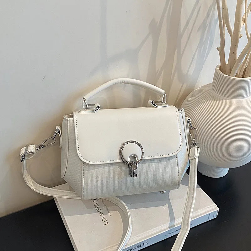 Ring clasp top handle crossbody bag – White bag beside a vase | BTendance
