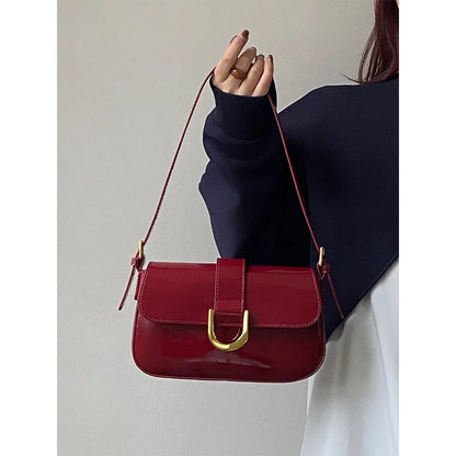 Flap shoulder bag with gold tone U clasp – Red bag held beside a dark sweater | BTendance