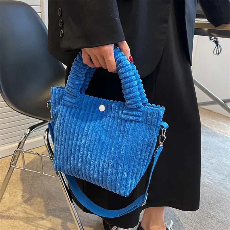 Ribbed plush handbag with rounded handles and long strap — blue held by model | BTendance