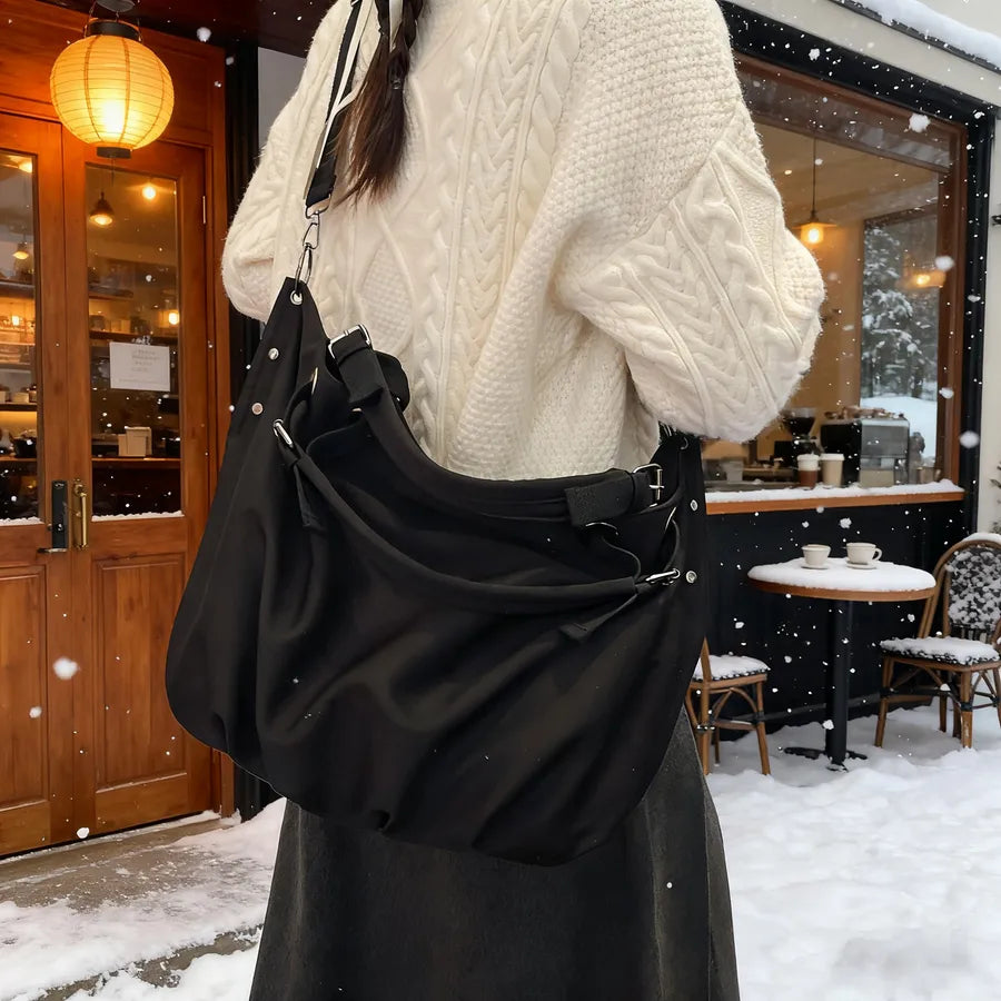 Slouchy nylon shoulder bag with contrasting grey handles — black worn over cream sweater | BTendance