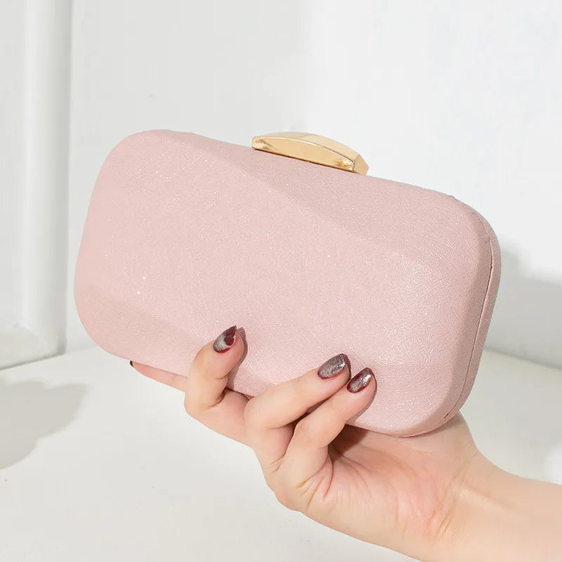 Rounded rectangular evening clutch with metal clasp — pink held in one hand | BTendance