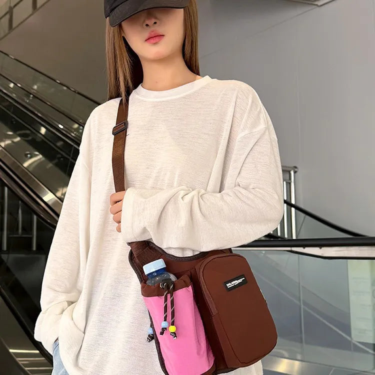 Crossbody bag with mesh bottle pocket and front zip pouch — brown with pink pocket worn crossbody | BTendance