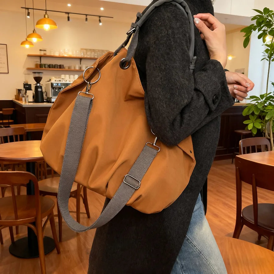 Slouchy nylon shoulder bag with contrasting grey handles — ochre worn on shoulder in cafe | BTendance