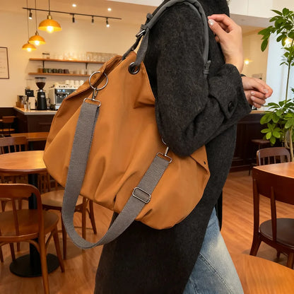 Slouchy nylon shoulder bag with contrasting grey handles — ochre worn on shoulder in cafe | BTendance