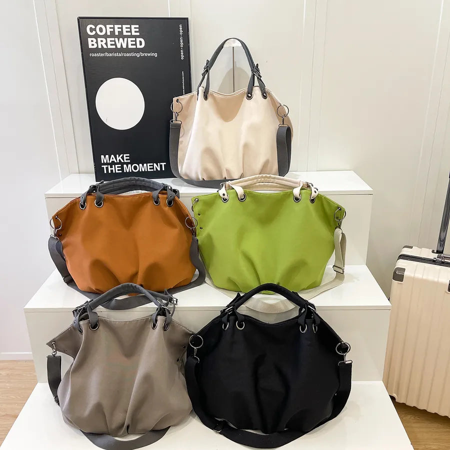 Slouchy nylon shoulder bag with contrasting grey handles — five colors arranged on display steps | BTendance