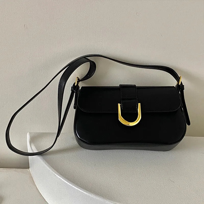 Flap shoulder bag with gold tone U clasp – Black bag displayed on a chair | BTendance