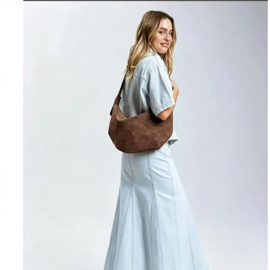 Crescent-shaped shoulder bag with adjustable strap — brown worn by model in pale blue outfit | BTendance