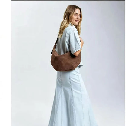 Crescent-shaped shoulder bag with adjustable strap — brown worn by model in pale blue outfit | BTendance