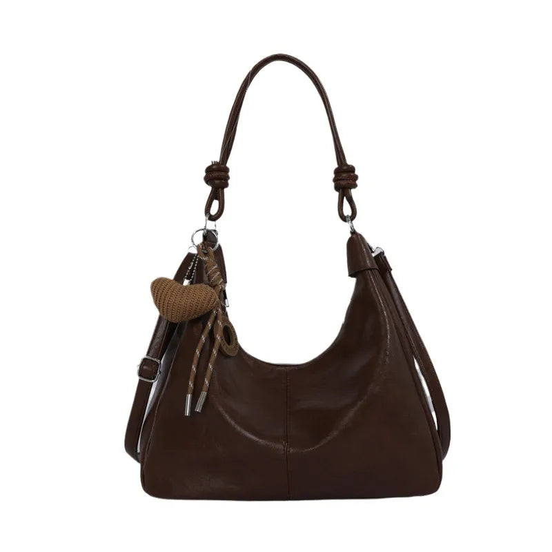 Slouchy shoulder bag with knotted strap and hanging charm — dark brown front view on white background | BTendance