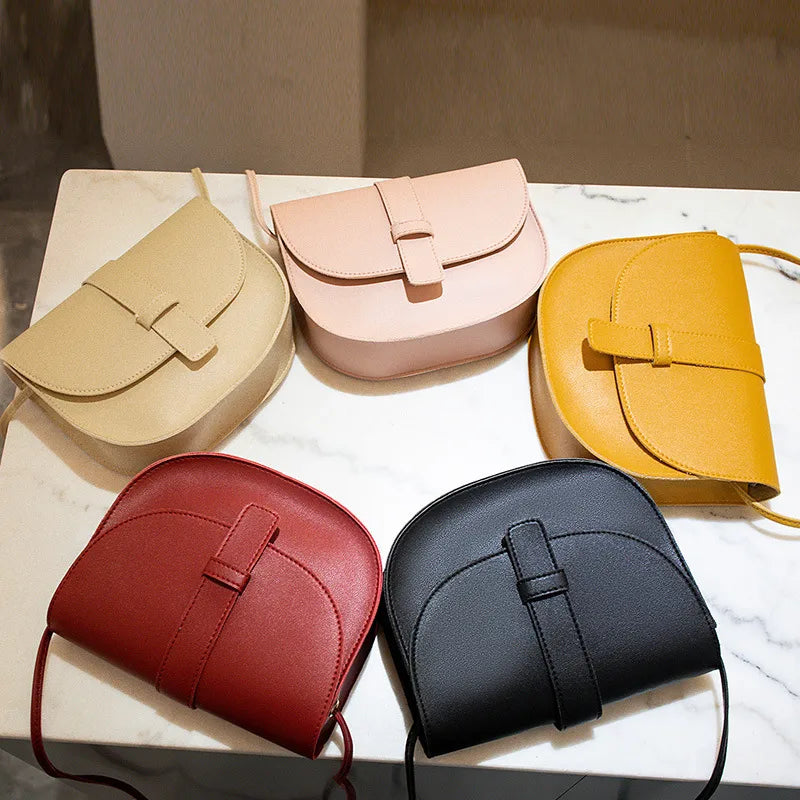 Rounded flap crossbody bag – Five colours arranged on a table | BTendance