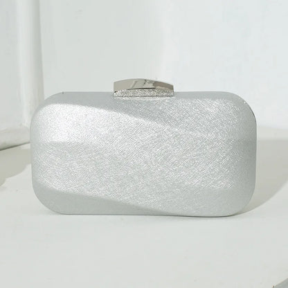 Rounded rectangular evening clutch with metal clasp — silver front view on table | BTendance