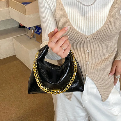 Soft handbag with gold tone chain – Black bag held against a knit top | BTendance
