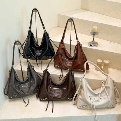 Slouchy shoulder bag with front zip and buckle details — five colors arranged on steps | BTendance