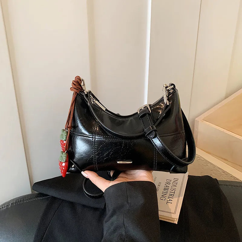 Glossy shoulder bag with strawberry charm – Black bag, front view in hand | BTendance