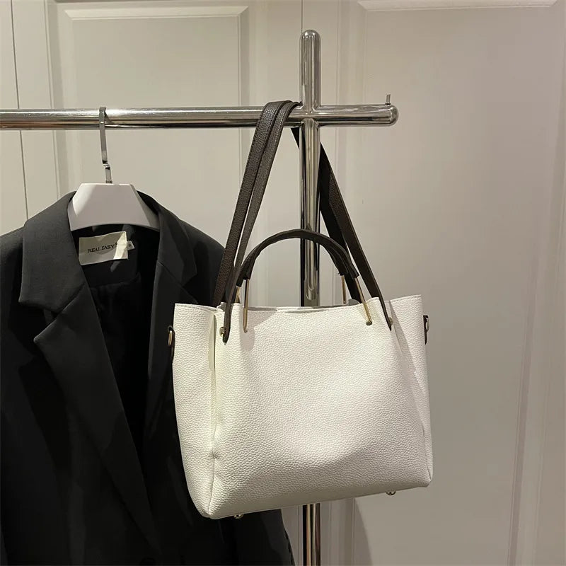 Textured bucket handbag with contrasting dark handles — white hanging on clothing rack | BTendance