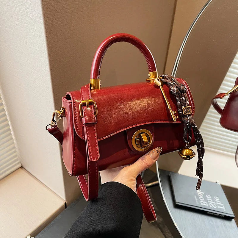 Structured top-handle flap handbag with round gold-tone clasp — red with scarf accent held in one hand | BTendance
