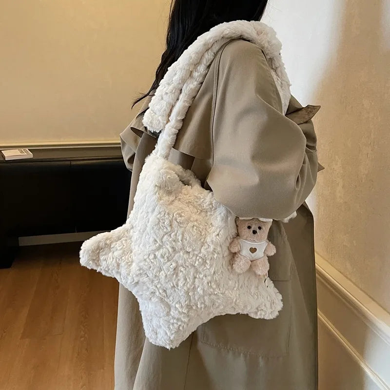 Star-shaped plush shoulder bag with small hanging charm — cream worn on shoulder | BTendance