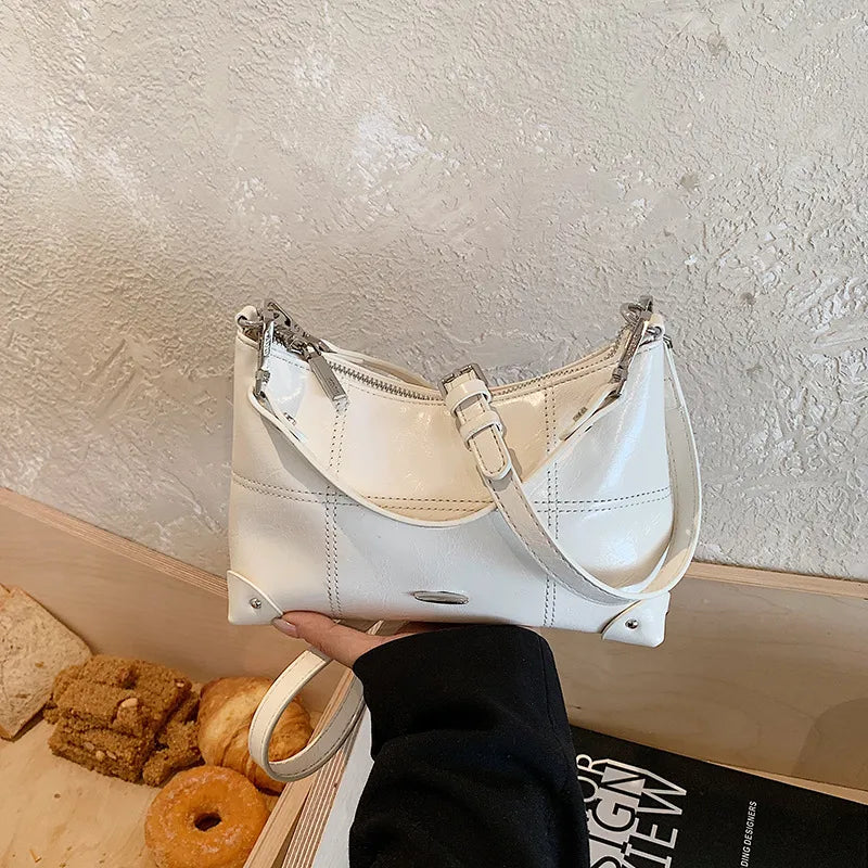 Glossy shoulder bag with strawberry charm – White bag held in one hand | BTendance